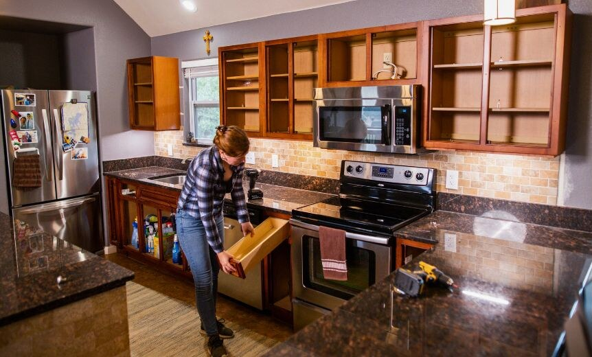 A homeowner removing old drawer fronts from a kitchen