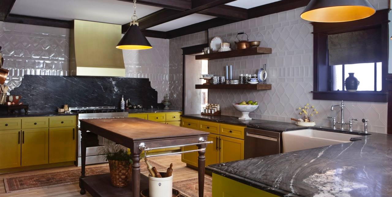 A kitchen with ochre cabinets and black marble counters